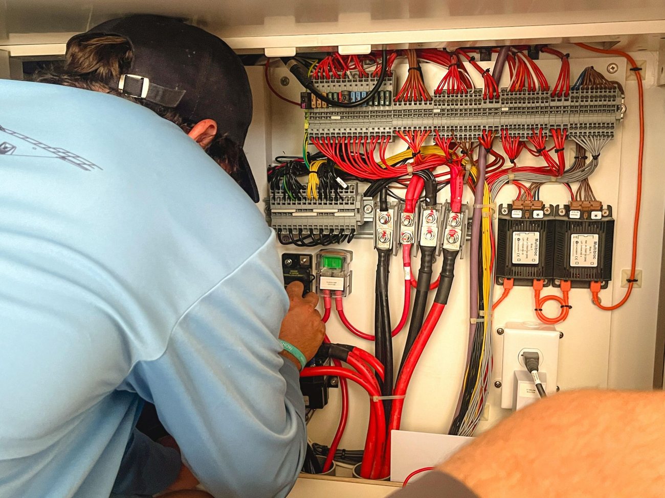 Working on the wiring behind a boat's electrical switchboard